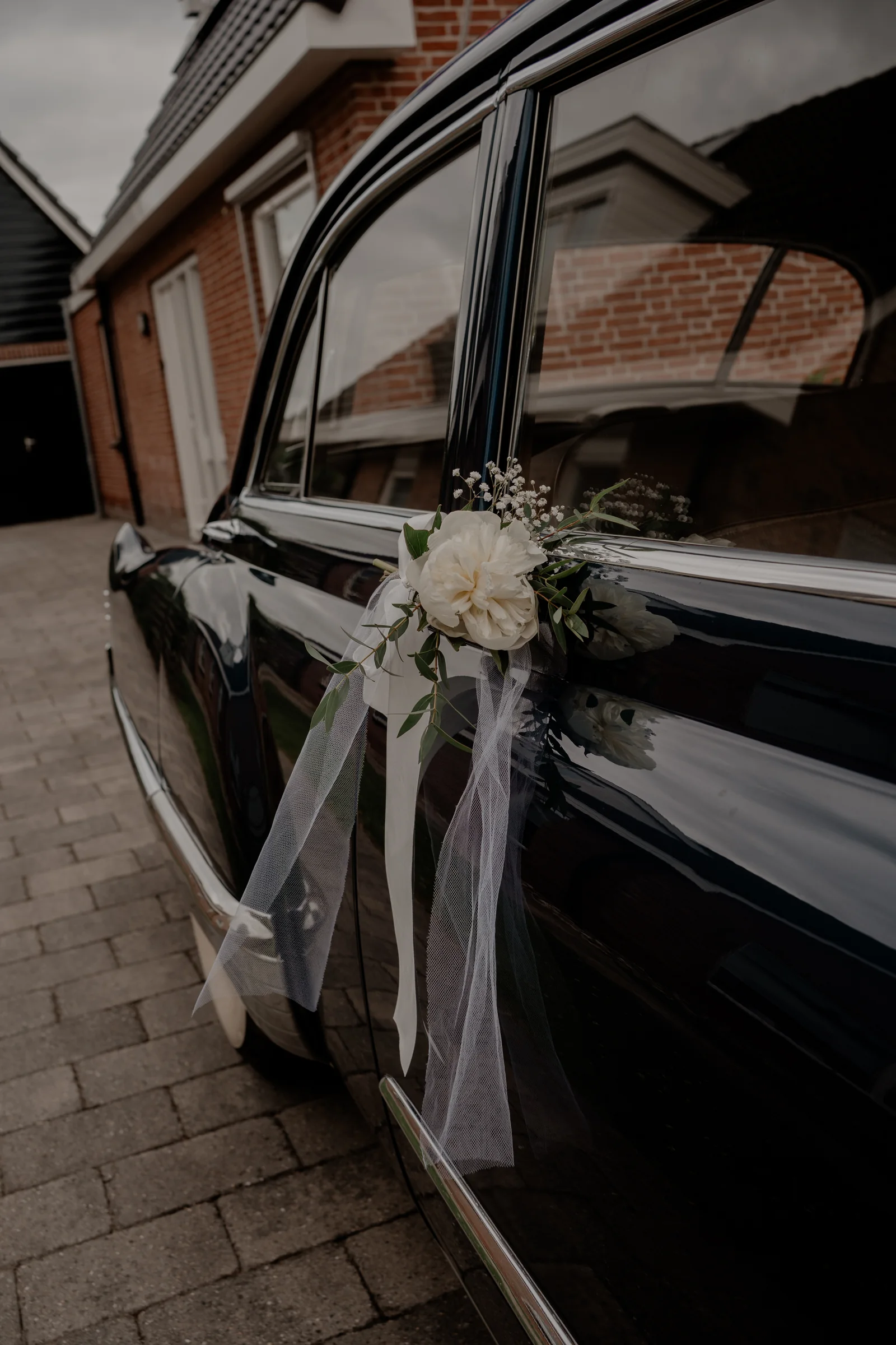 Witte bloemen en linten aan de deur van de Cadillac