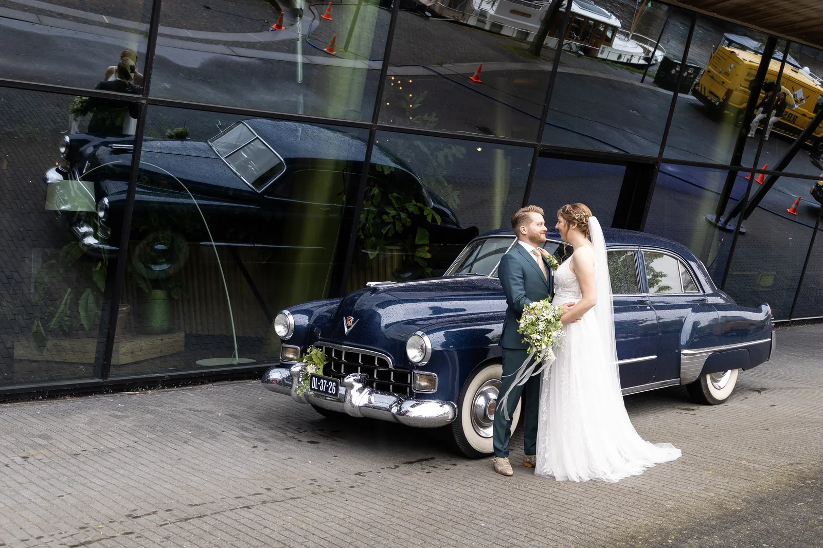 Erik en Maaike naast de Cadillac voor een moderne glazen gevel