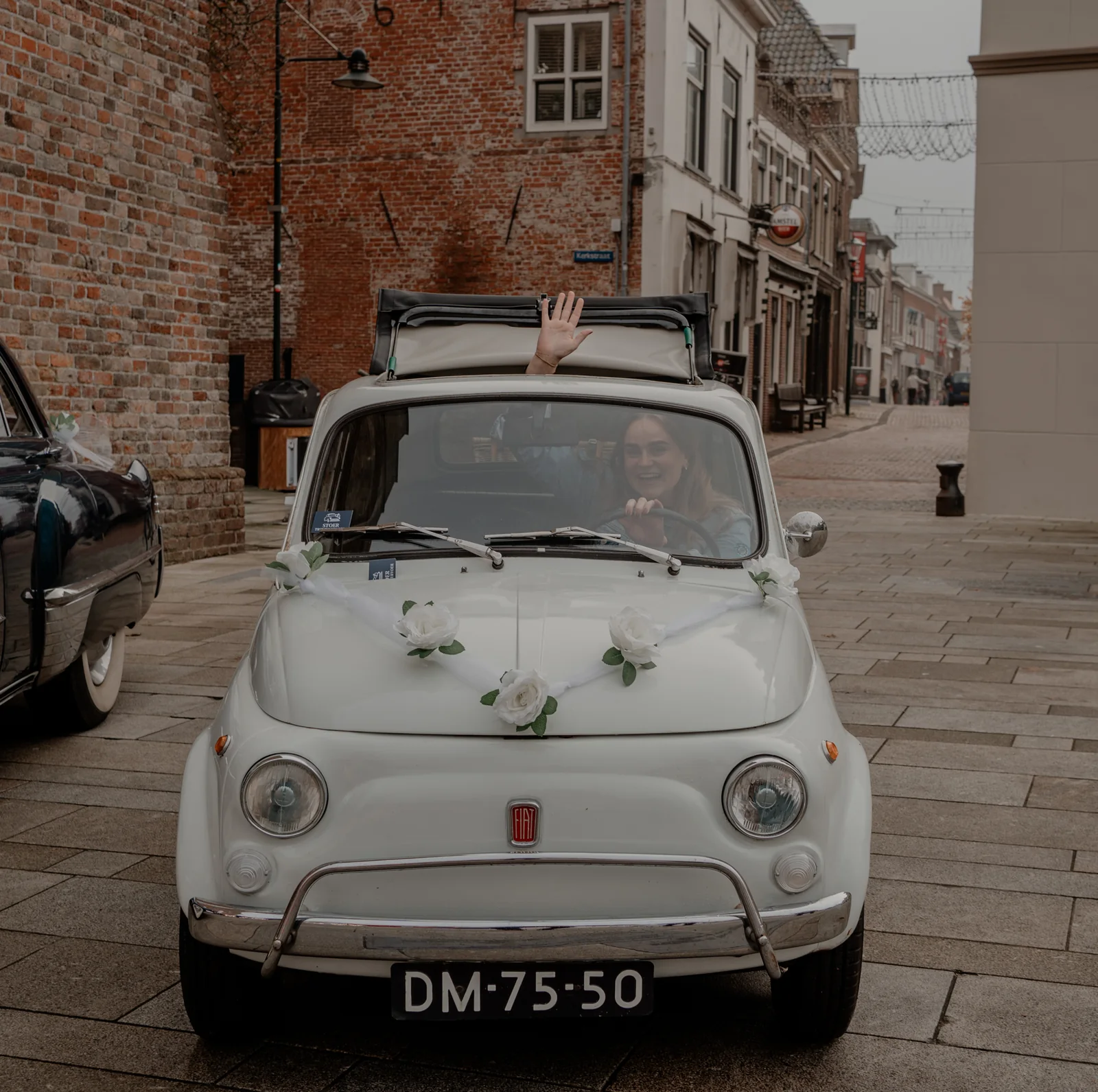 Witte Fiat 500L uit 1970 met open vouwdak voor een kerk