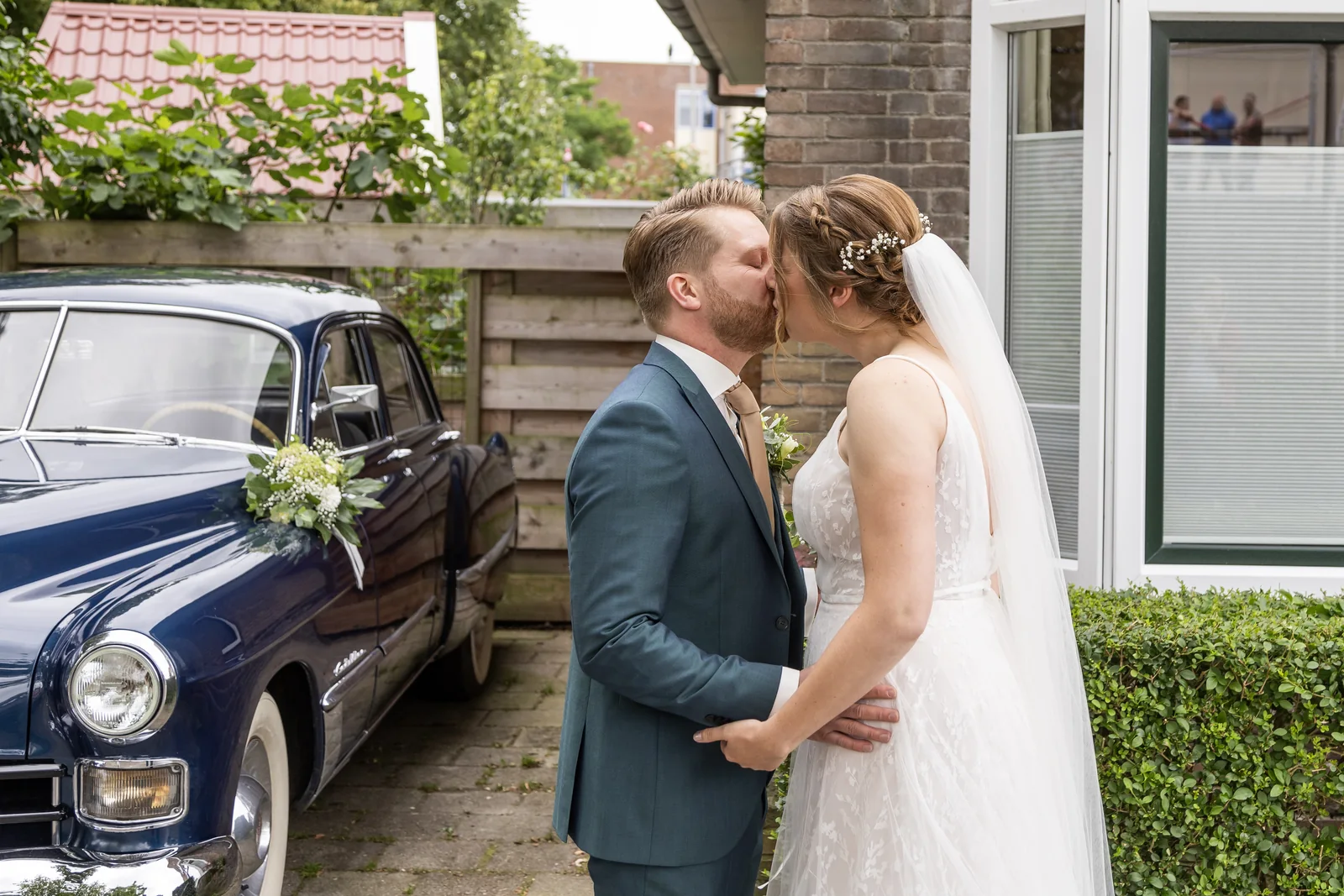 Erik en Maaike kussen naast de Cadillac op hun trouwdag