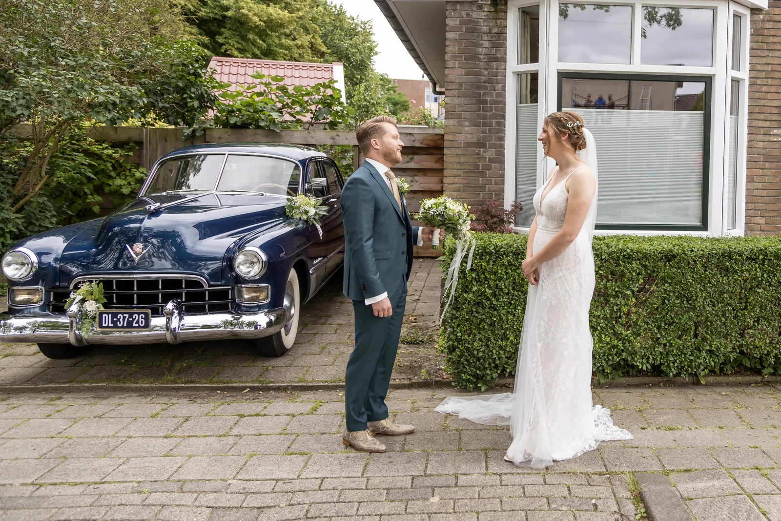 Erik en Maaike kijken elkaar aan naast de Cadillac op hun trouwdag
